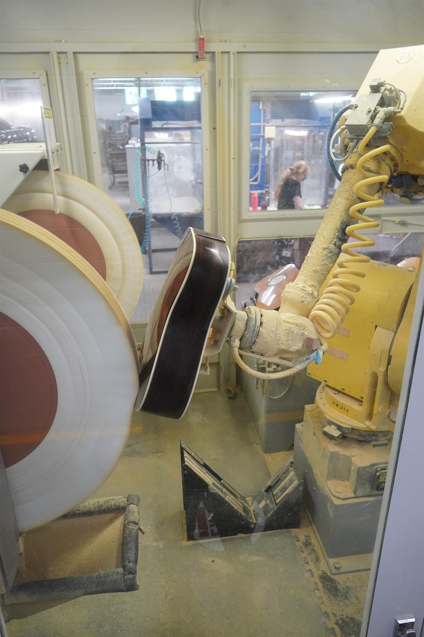 A robotic arm finishing guitars in a factory.